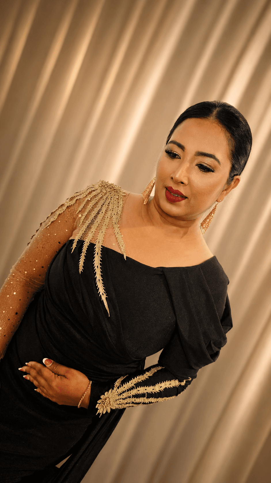 Formal glam makeup with a black and gold embellished off-shoulder gown